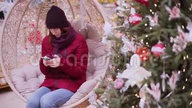 一个年轻漂亮的女人在圣诞商店，使用智能手机。 女人在商店里走来走去挑选圣诞装饰品